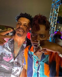two men standing next to each other at a party
